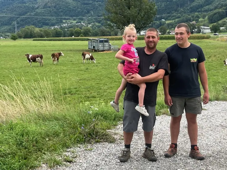 Deux éleveurs avec une petite fille devant un près avec des montbéliardes en Haute-Savoie