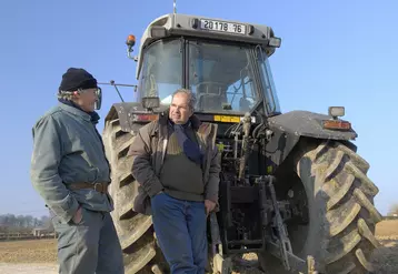 Deux agriculteurs aux cheveux gris discutant devant un tracteurs