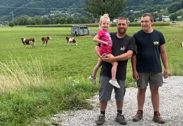 Deux éleveurs avec une petite fille devant un près avec des montbéliardes en Haute-Savoie