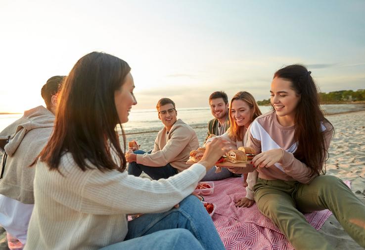 Un groupe de jeunes partage un pique-nique sur la plage