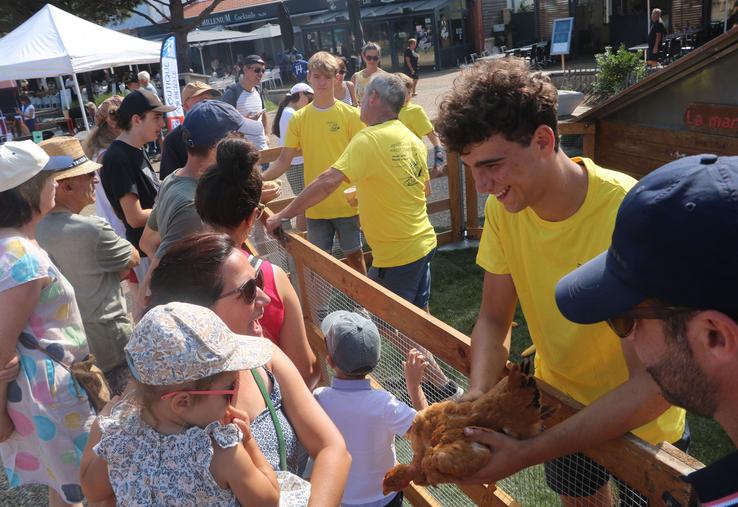 Un jeune agriculteur présente un poulet a des visiteuses
