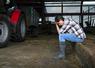 Dans un hangar près de son tracteur, un agriculteur assis se tient la tête dans les mains