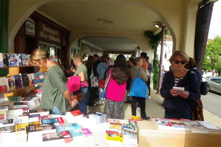 Personnes feuilletant des livres sous les arches de la place centrale de Geaune