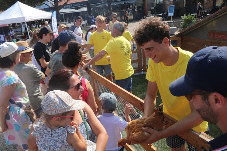 Un jeune agriculteur présente un poulet a des visiteuses