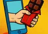 une main sort d'un smartphone et tend une barre de confiserie