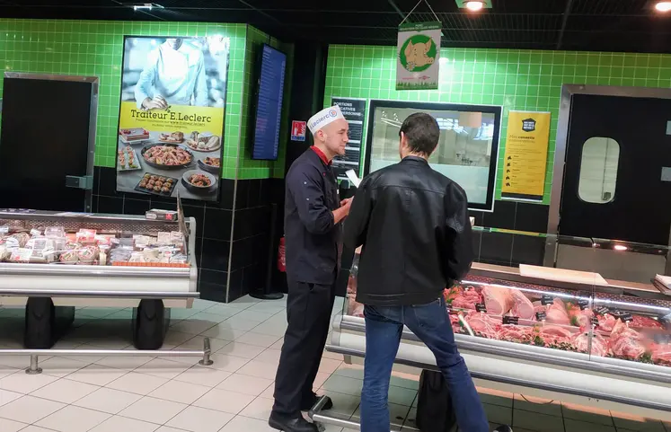 deux hommes discutent au rayon boucherie du supermarché