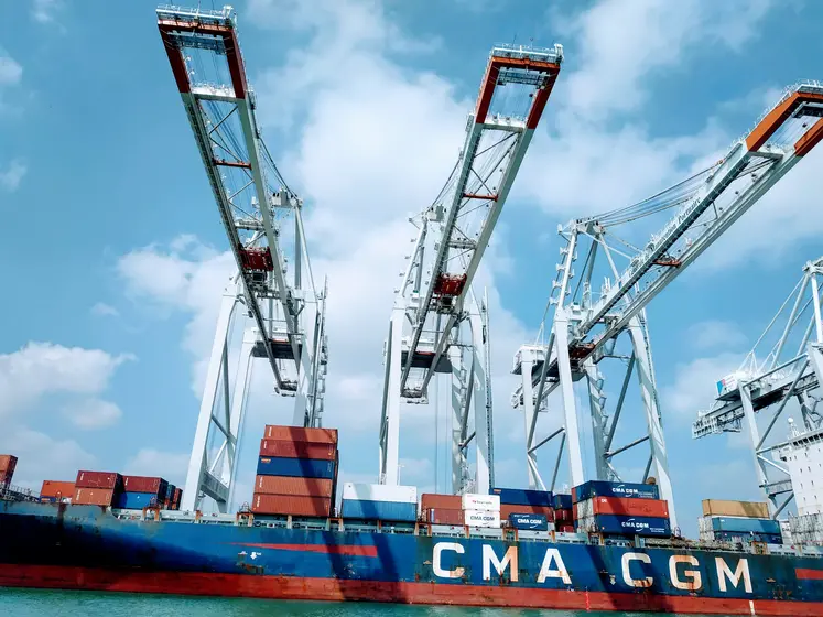 bateau porte conteneur au port devant des grues