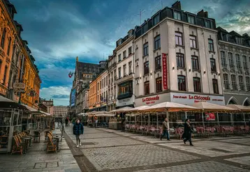 un groupe de personnes marchant dans une rue à côté de grands immeubles