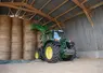 <em class="placeholder">Tracteur John Deere avec chargeur devant un stockage de balles de paille rondes.</em>