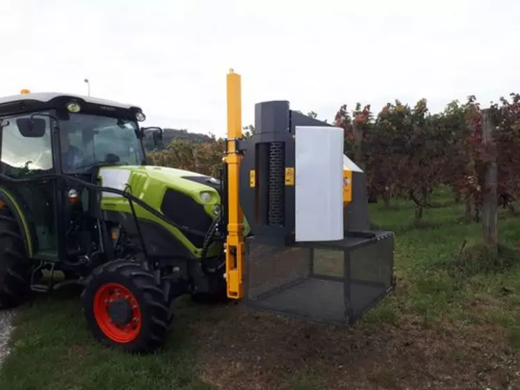 Machine à récolter les feuilles rouges d'un vignoble, montée devant un tracteur spécialisé Claas.