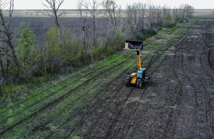 Un opérateur pilote le tracteur à distance depuis le godet d'un chargeur télescopique.