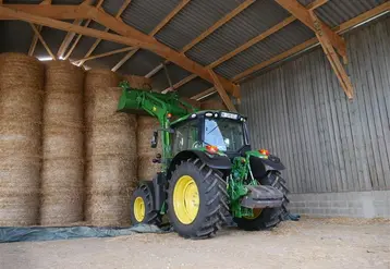 <em class="placeholder">Tracteur John Deere avec chargeur devant un stockage de balles de paille rondes.</em>