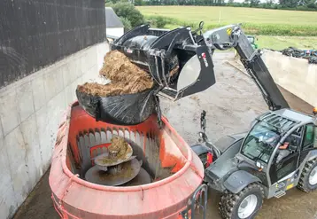 <em class="placeholder">Benne à grappin coupe-balle Xtra’Shark de Magsi chargeant une balle d'enrubannage dans une remorque mélangeuse à vis verticale.</em>