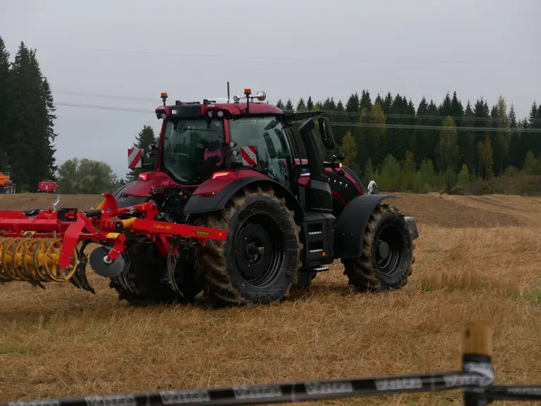 Tracteur Valtra série T de sixième génération roulant dans un champ avec un outil porté.