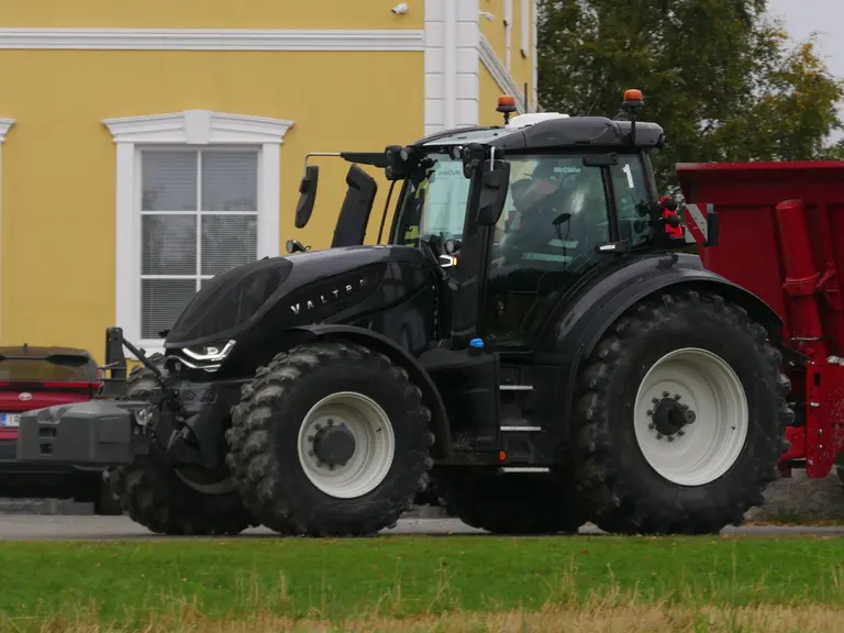 Tracteur Valtra série T de sixième génération attelé à une benne TP et roulant sur la route.