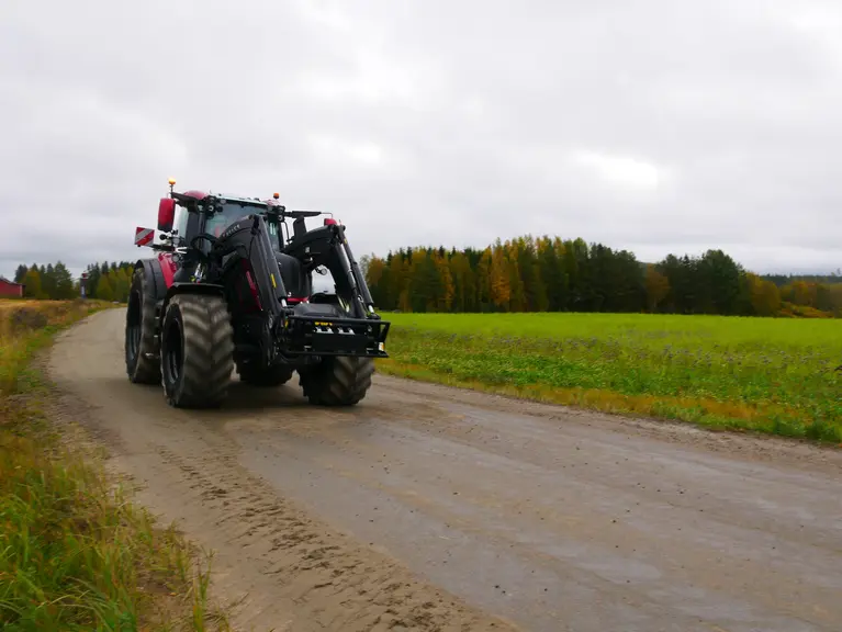 Tracteur Valtra série T de sixième génération avec un chargeur frontal et roulant sur la route.