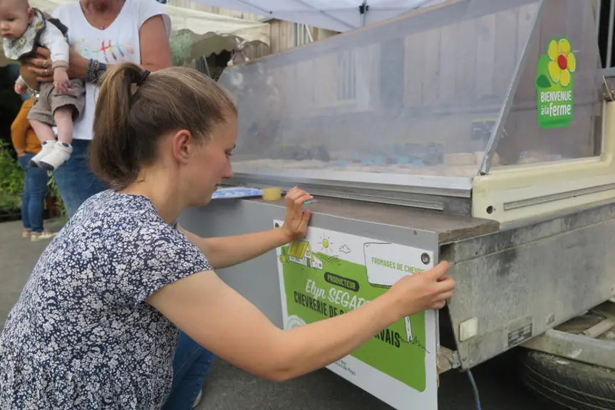Une fromagère fermière installe une affichette d'identification
