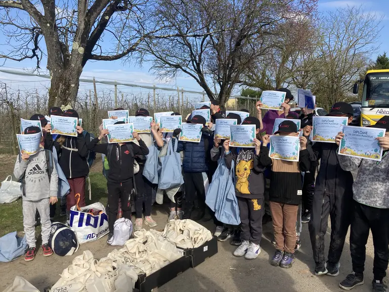 des enfants tiennent devant leur visage un diplôme de "citoyen planteur"