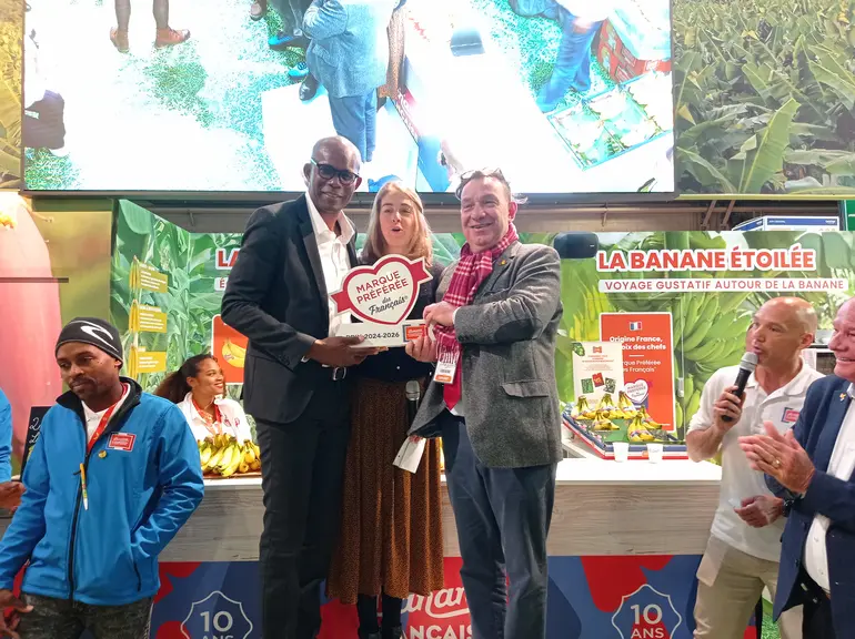 Trois personnes tiennent un prix sur un podium, sur un stand au salon de l'agriculture