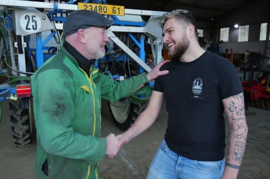 agriculteurs, un cédant un repreneur, qui se serrent la main devant un tracteur