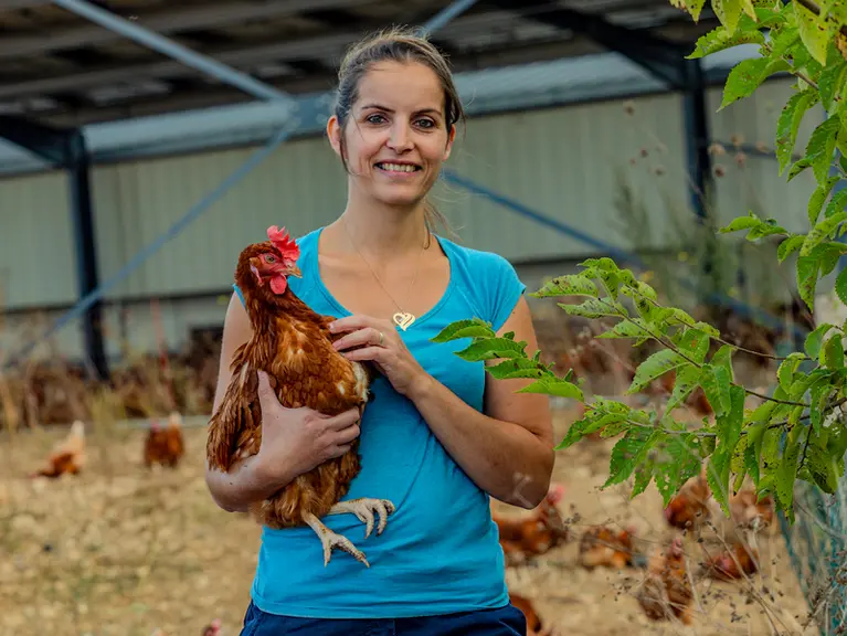 L'éleveuse Lucie Mainard avec une poule pondeuse dans les bras.
