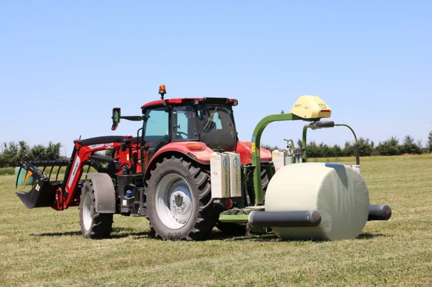 L'enrubanneuse portée Krone EasyWrap 150 dépose les balles en écartant ses rouleaux d'entraînement. © M. Portier