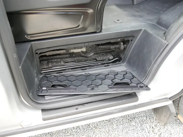Un espace est prévu au niveau du marchepied droit du Ford Transit Custom pour ranger le cric et les outils nécessaires au remplacement d'une roue. © D