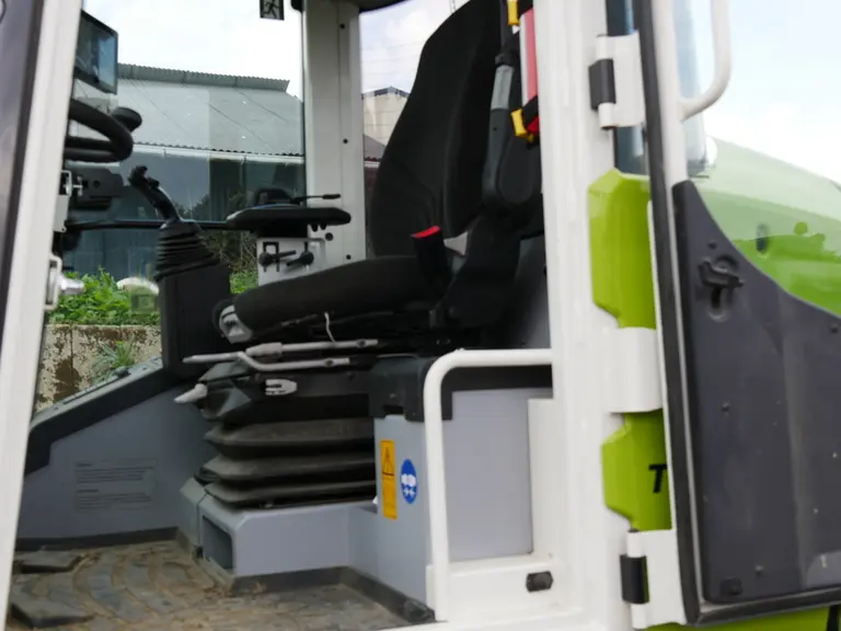 La chargeuse Claas Torion 738 T Sinus dispose dans grand bac de rangement fermé à gauche du siège chauffeur.