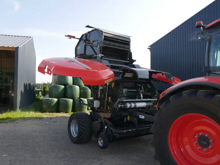 Les grands carters latéraux de la presse à balles rondes Kubota BV 5200 Plus sont maintenus ouverts par des vérins oléopneumatiques. Leur dessin évite l'accumulation de poussière.