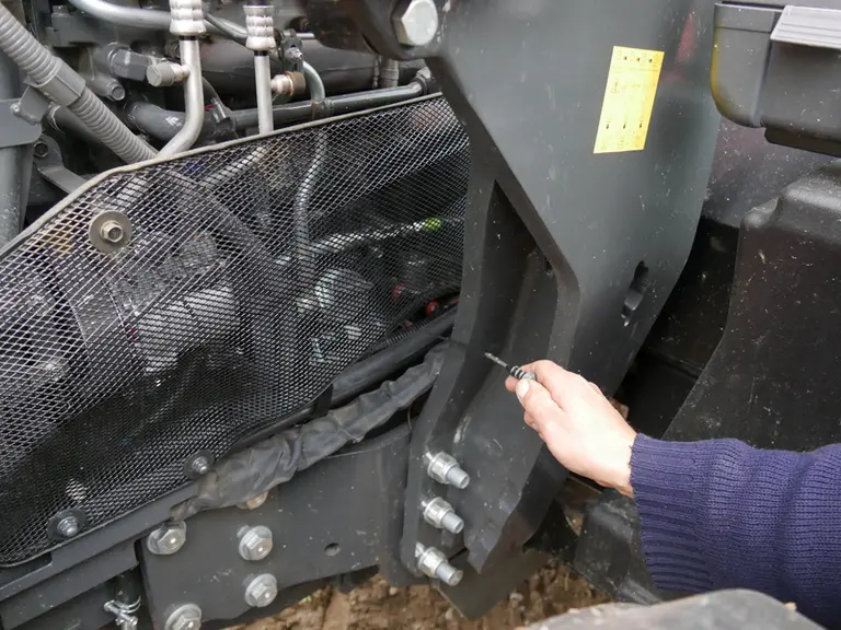 La jauge à huile moteur du tracteur Kubota M6 est accessible du côté gauche.