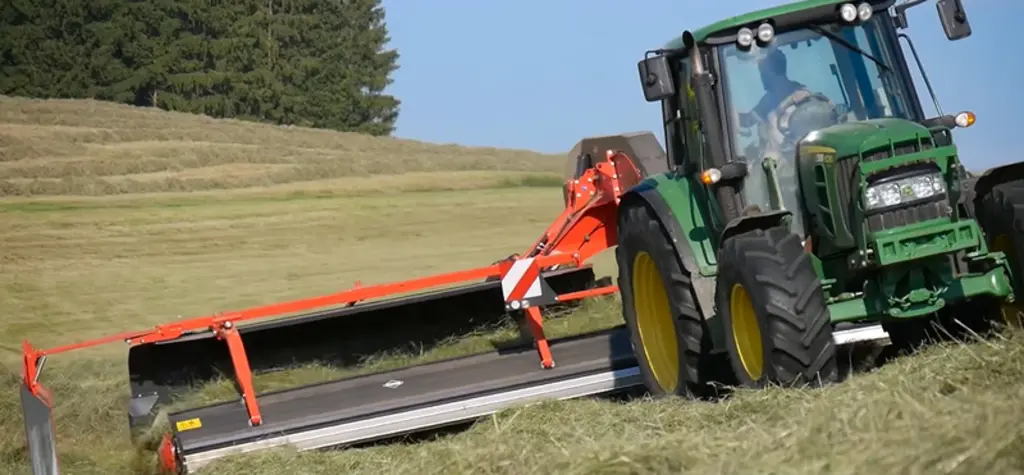 L'andaineur à tapis Kuhn Merge Maxx 950 est attelé à un tracteur de 95 ch.