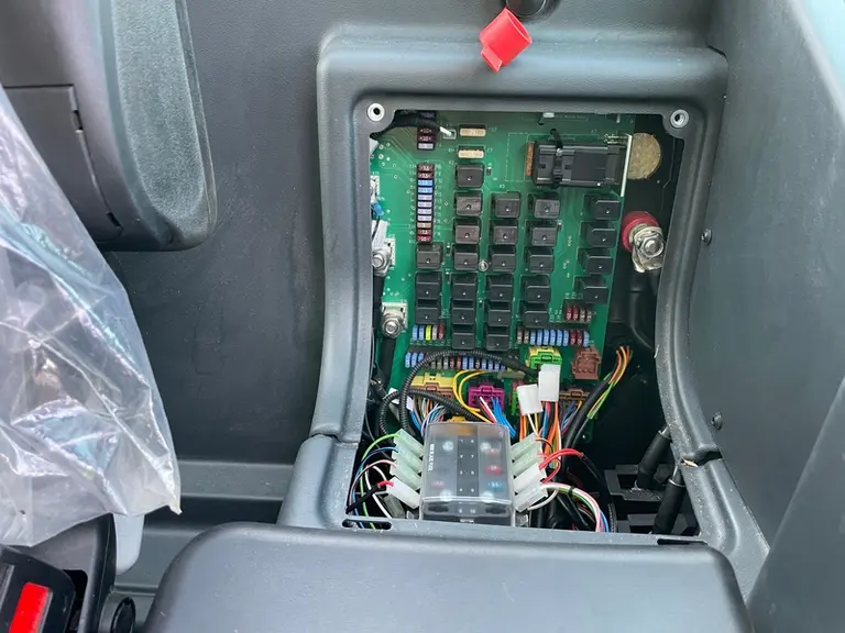 La boîte à fusibles et relais est facilement accessible derrière le siège passager de la chargeuse Schäffer 8620 T-2.