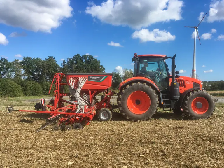 Semoir Kverneland dans un champ avec un tracteur Kubota