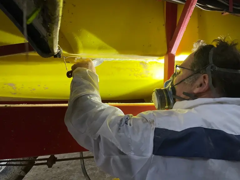 Avant que le plastique de la soudure ait complétement refroidi, le réparateur rappuie la zone avec une spatule. 