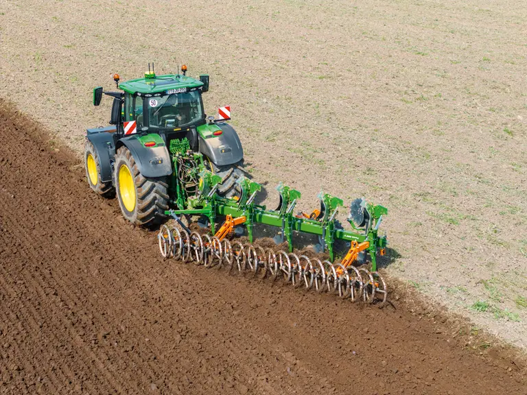 Charrue Amazone équipé d'un rouleau tasseur attelé à un tracteur John Deere