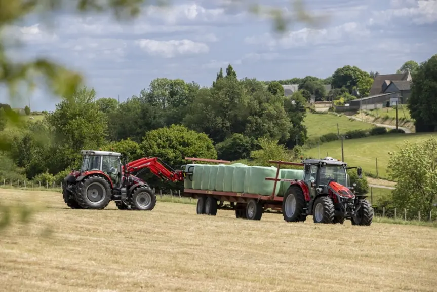 Tracteur Massey Ferguson MF 5S Dyna-VT équipé d'un chargeur frontal chargeant avec des balles rondes d'enrubannage u