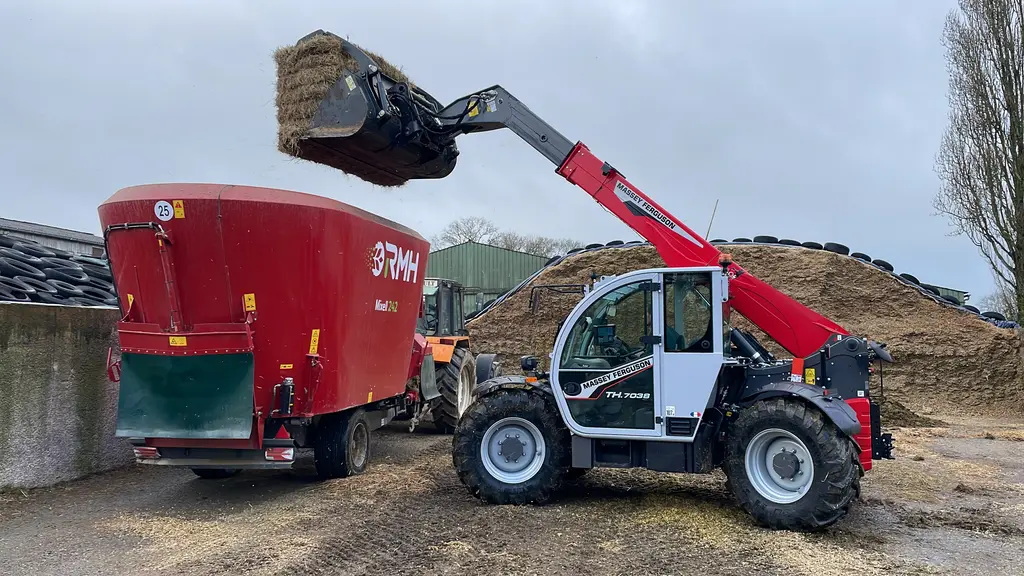 Chargeur télescopique Massey Ferguson TH.7038 au chargement d'un remorque mélangeuse RMH