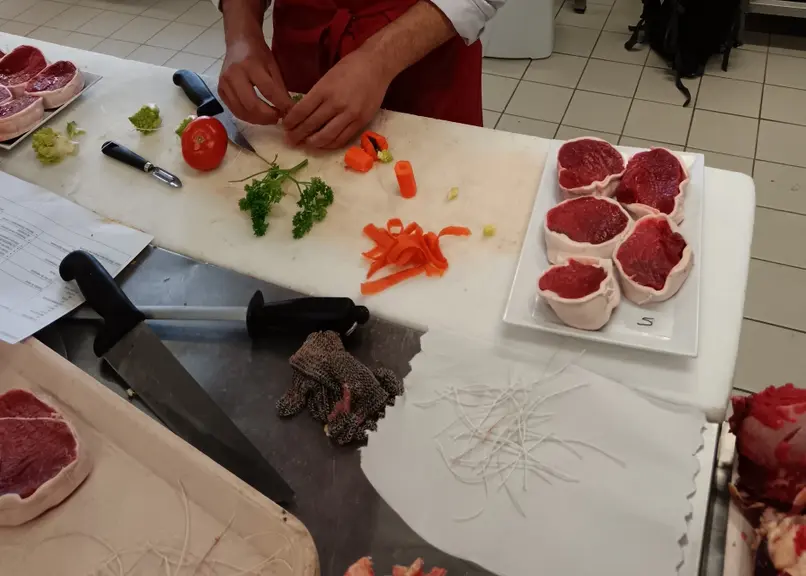 Un jeune boucher prépare des pavés de bœuf.