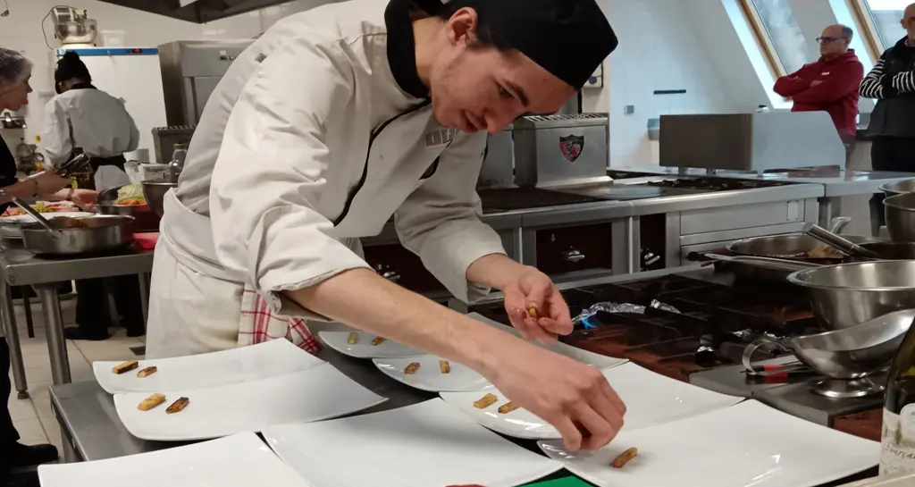 Une jeune cuisinier dresse des pavés de bœuf.