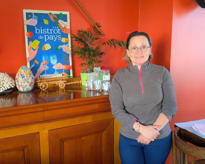 cathy la gérante de l'auberge de valcivières pose devant le panneau bistrot de pays