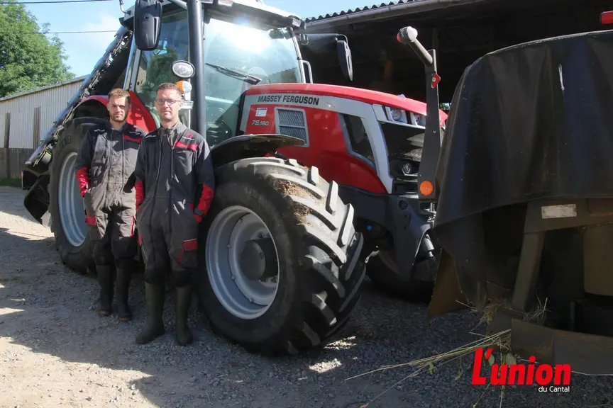 deux agriculteurs posent devant un tracteur rouge
