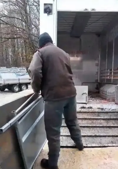 Une personne installe des claies coulissantes sur un quai de chargement.