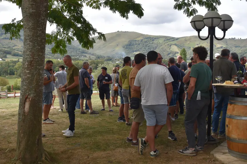 Personnes discutant dehors devant un paysage pyrénéen.
