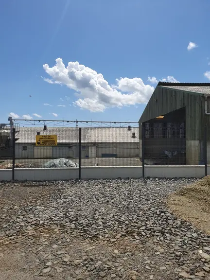 Le coproduit solide de la station de traitement du lisier est chargé dans un camion par dessus la clôture qui sépare la zone d’élevage de la zone prof