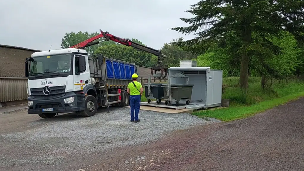 Le bac est repris par la grue du camion, commandée par un joystick puis est reposé sur le plateau. © SecAnim