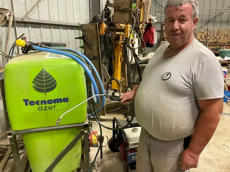 Avec une lance dans chaque main, Gabriel Astier peut arroser les plants depuis son tracteur.