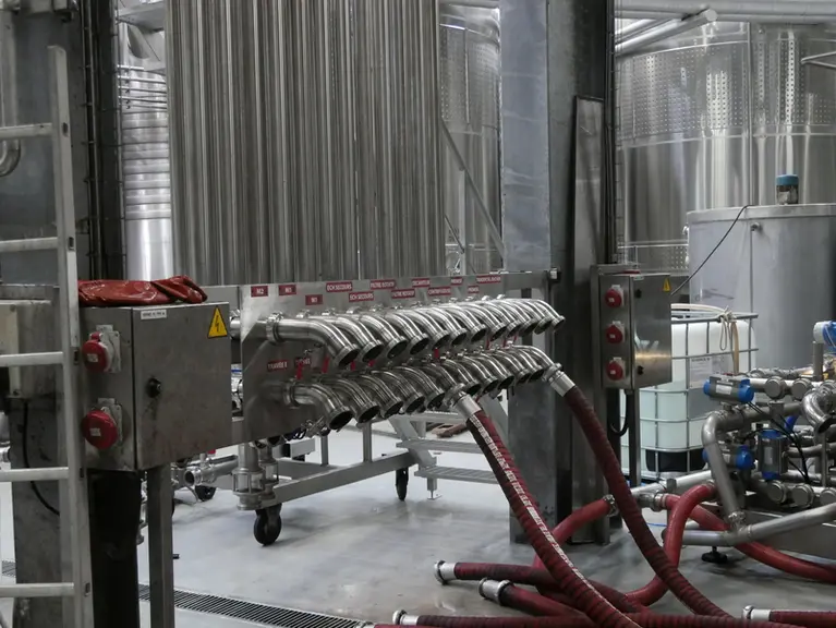 Un système de tuyauterie fixe en inox parcourt la cave. Ainsi les opérateurs n'ont pas à brancher et débrancher des lignes entières de tuyaux.
