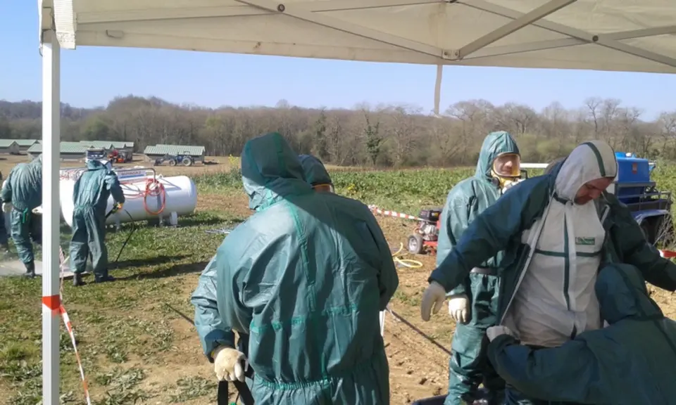 Au passage du sas de désinfection, les opérateurs revêtent une seconde tenue, des gants, un masque à cartouche et leurs bottes sont aspergées de désin