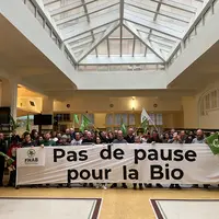 Des agriculteurs bio devant une banderole avec le message "pas de pause pour la bio"
