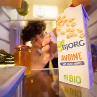 Jeune garçon prenant un paquet d'avoine bio à la marque Bjorg dans son frigo